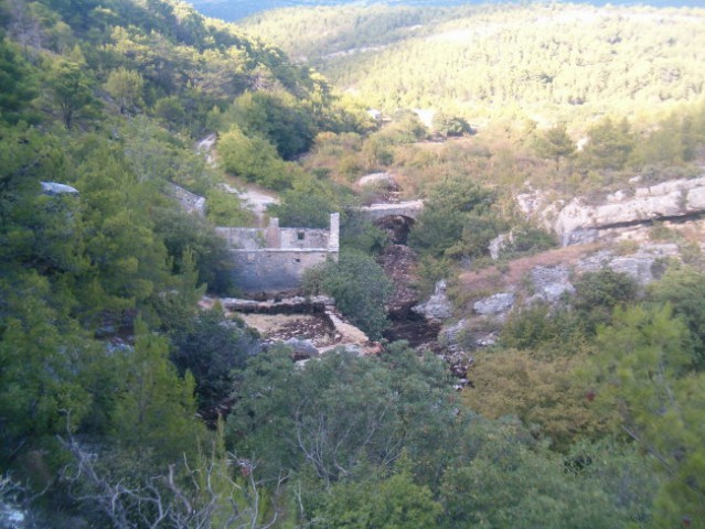 Pogled na zapuščen mlin ter kamnit most v kanjonu Karinščice