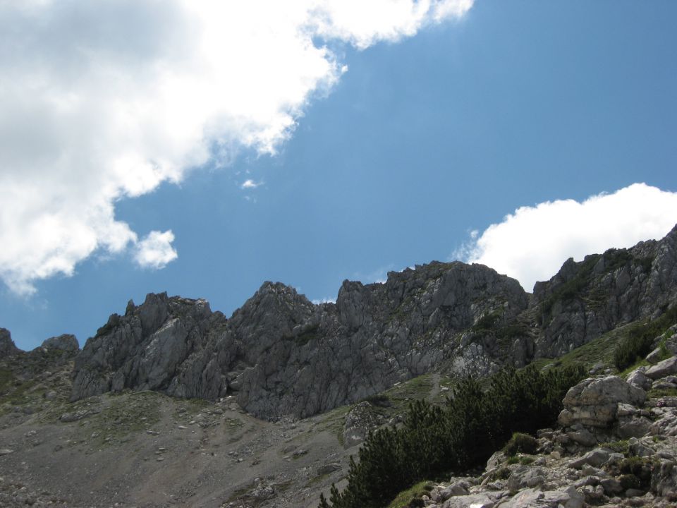 pogled nazaj na stezo ob zg. robu melišča, ki skrene desno v plezalni vršni del