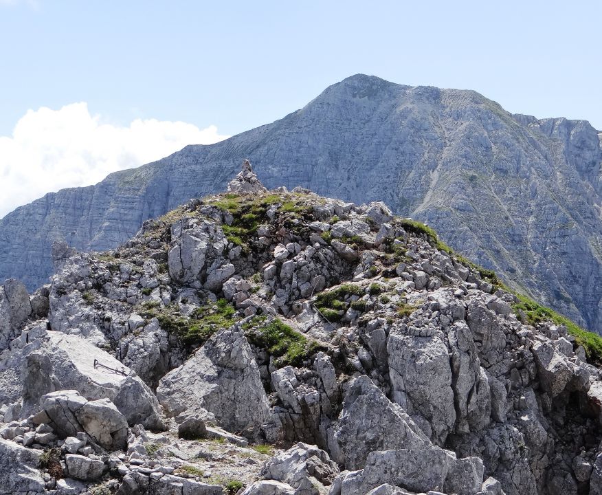 možic na drugem vrhu košutice, zadaj nad njim veliki vrh v košuti