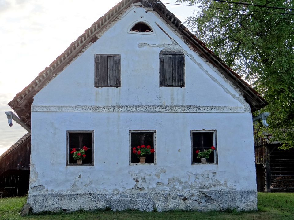 stara hiška s tremi cvetočimi okni