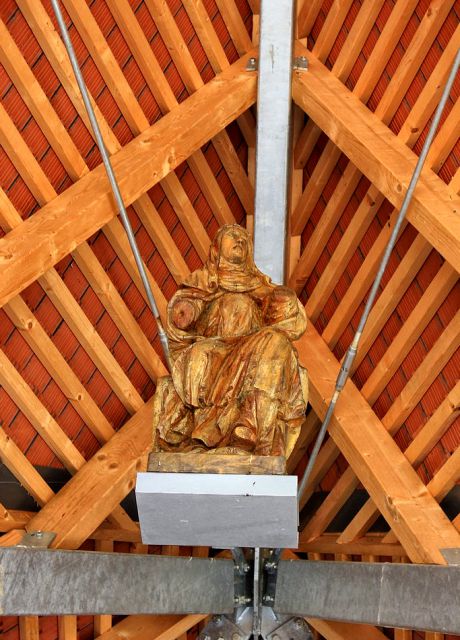 Pod ostrešjem je pritrjen lesen kip sv. jere