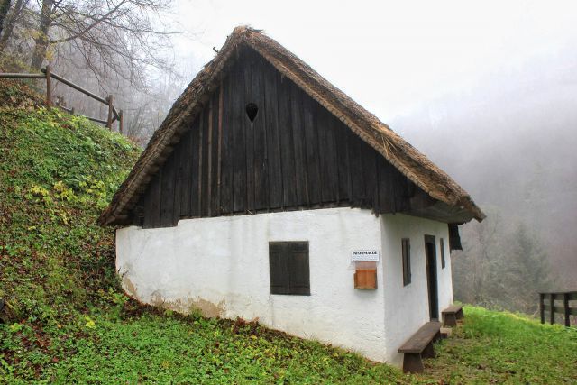 Stara hiška s slamnato streho na začetku vzpona na ajdovski gradec