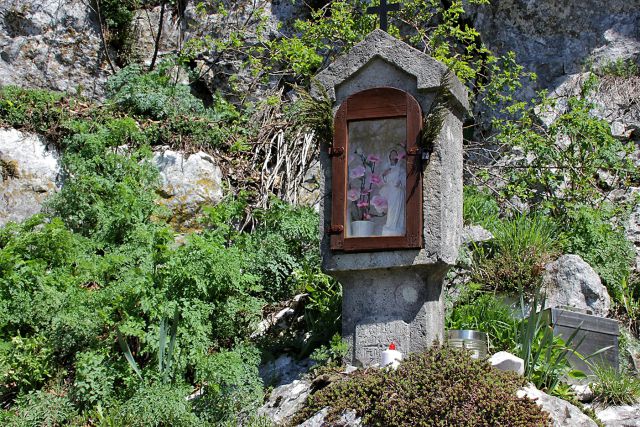 Starinsko znamenje pod podrto goro, zraven vpisna skrinjica